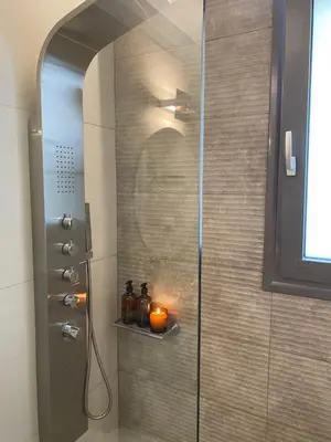 a shower with a candle on a shelf in a bathroom at NEW 2BD Aprt with Shared Rooftop Pool B3 in Athens