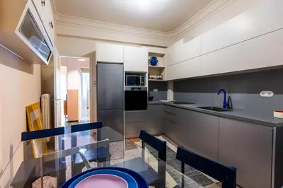 a kitchen with a glass table and blue chairs at Ernesto Apartment in Athens