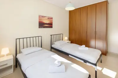 a bedroom with two beds and a cabinet at Urban Oasis with Acropolis Views by GHH in Athens