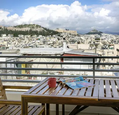 a wooden table on a balcony with a view of a city at Urban Oasis with Acropolis Views by GHH in Athens