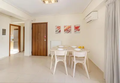 a white dining room with a table and chairs at Urban Oasis with Acropolis Views by GHH in Athens