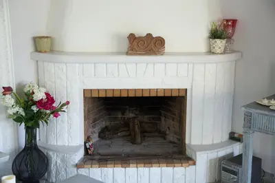 a white brick fireplace with a white mantle and a vase of flowers at Lili and Blue - Charming house in Porto Rafti