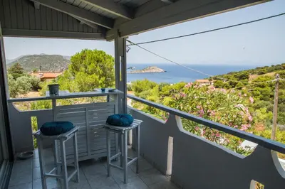 a balcony with two stools and a view of the ocean at Lili and Blue - Charming house in Porto Rafti