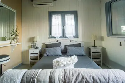 a bedroom with a large bed and two windows at Lili and Blue - Charming house in Porto Rafti