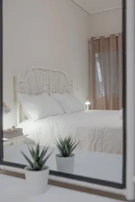 a bedroom with a white bed and a mirror at KalaGans CosyHome in Athens