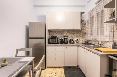 a kitchen with white cabinets and a stainless steel refrigerator at KalaGans CosyHome in Athens