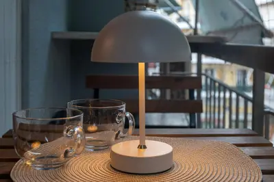 a table with a lamp and two glasses on it at KalaGans CosyHome in Athens