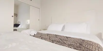 a white bedroom with two beds with white sheets at Bee Home - Apartment in Kypseli Central Athens in Athens