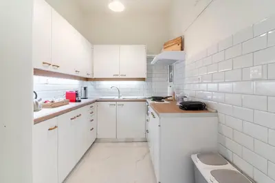 a white kitchen with white cabinets and a sink at Bee Home - Apartment in Kypseli Central Athens in Athens