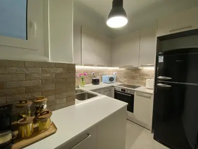 a kitchen with white cabinets and a black refrigerator at 2 Bedroom Apartment near Prestigious Kolonaki Square in Athens