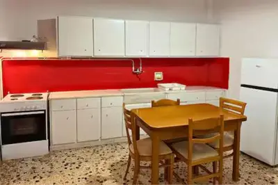 a kitchen with a table and a red wall at Live like a Local in Athens in Piraeus