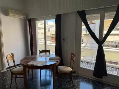 a dining room with a table and chairs and a window at Live like a Local in Athens in Piraeus