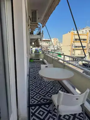 a balcony with a table and chairs on a building at Live like a Local in Athens in Piraeus