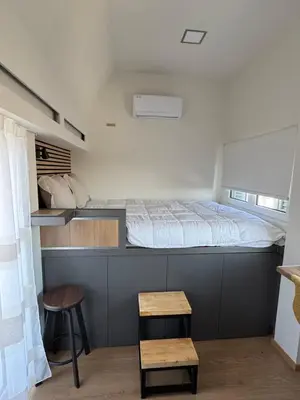 a small bedroom with a bed and a stool at Panormou Cityview Loft in Athens
