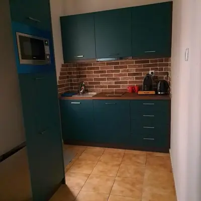a kitchen with green cabinets and a brick wall at Urban Nest Apartments in Athens
