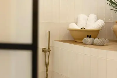 a bathroom with a shelf with towels and a bowl of towels at Aristotelus Studio Jacuzzi & Acropolis View in Athens