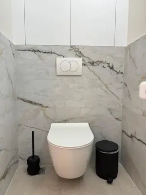 a bathroom with a white toilet in a marble wall at Harbour Getaway in Piraeus