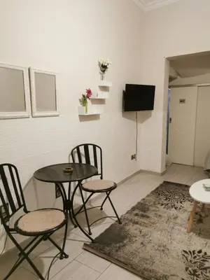 a room with a table and two chairs and a television at Emily's house in Athens