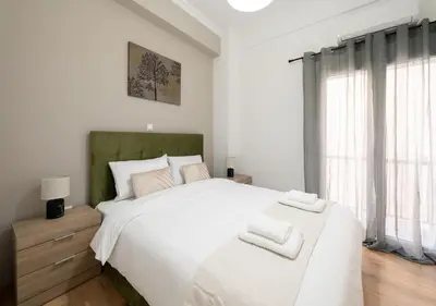 a bedroom with a large white bed with two towels at Modern flat 7' from Subway Stations in Athens