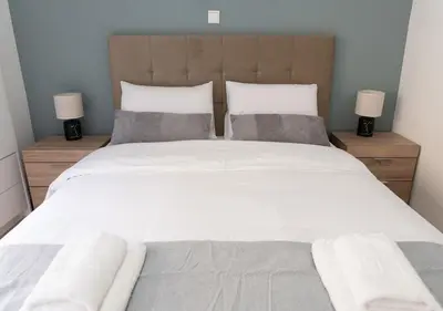 a bedroom with a large white bed with two lamps at Modern flat 7' from Subway Stations in Athens