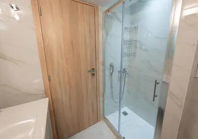 a shower with a glass door in a bathroom at Modern flat 7' from Subway Stations in Athens