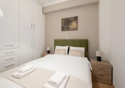a white bedroom with a large bed with two white towels at Modern flat 7' from Subway Stations in Athens