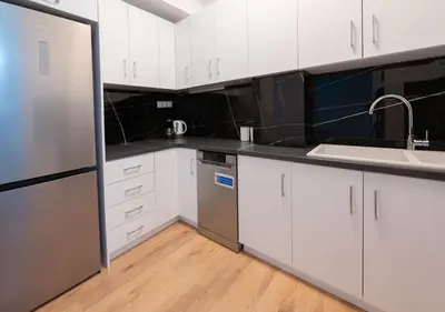 a kitchen with white cabinets and a stainless steel refrigerator at Modern flat 7' from Subway Stations in Athens