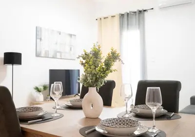 a dining room table with glasses and a vase with flowers at Modern flat 7' from Subway Stations in Athens