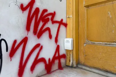 a wall covered in red graffiti next to a door at City Wanderer Modern Loft in Athens