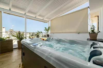 a large bath tub in a room with a large window at Central penthouse studio with Jacuzzi in Varkiza in Vari