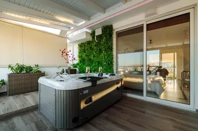 a bathroom with a tub and a view of a bedroom at Central penthouse studio with Jacuzzi in Varkiza in Vari
