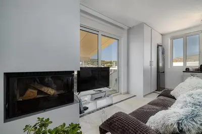 a living room with a fireplace and a tv at Central penthouse studio with Jacuzzi in Varkiza in Vari