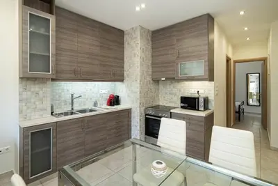 a kitchen with wooden cabinets and a glass table at Acropolis Nest in Athens