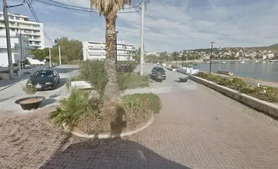 a sidewalk with a palm tree and cars on a street at Home by the Sea in Porto Rafti in Porto Rafti