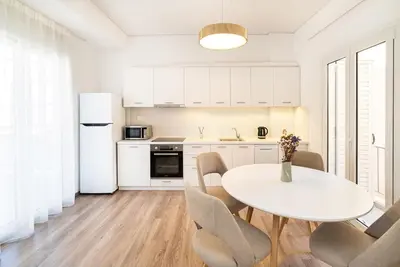 a white kitchen with a white table and chairs at Athens Casa Dell 'Imperatore in Athens