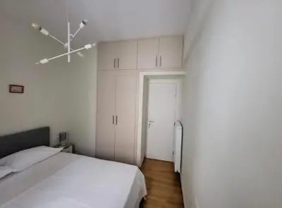 a white bedroom with a bed and a door at 2 bd renovated flat at acropolis in Athens