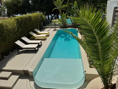 a swimming pool with lounge chairs and a palm tree at VILLA LAGUNA BLUE - Kavouri Vouliagmeni BEACH FRONT in Athens