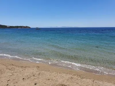 a beach with the ocean and a boat in the water at VILLA LAGUNA BLUE - Kavouri Vouliagmeni BEACH FRONT in Athens
