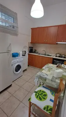 a kitchen with a table and a washing machine at Armonia's Apartment in Piraeus
