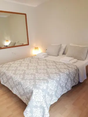 a bedroom with a large white bed with a mirror at COZY Apt BY THE SEA AT VOULIAGMENI in Athens
