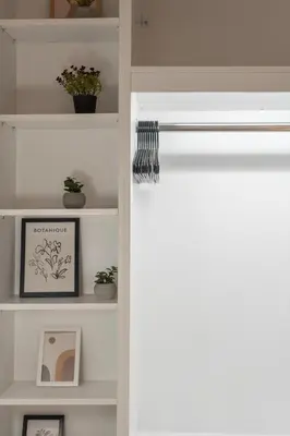 a white book shelf with plants and pictures on it at 