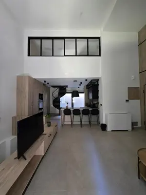 a living room with a tv and a dining table at Spacious Minimalistic Loft ,5 minutes walk to Metro in Athens