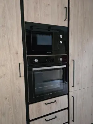 a black oven in a kitchen with wooden cabinets at Spacious Minimalistic Loft ,5 minutes walk to Metro in Athens