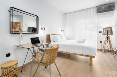 a bedroom with a bed and a desk with a laptop at Rizes Suites Metro Dafni in Athens