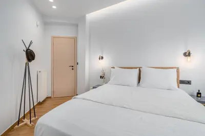 a white bedroom with a large white bed with white pillows at Rizes Suites Metro Dafni in Athens