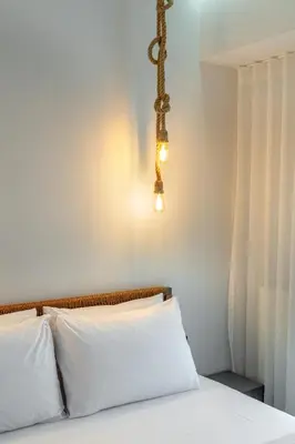 a bedroom with a bed with white sheets and a light fixture at Rizes Suites Metro Dafni in Athens