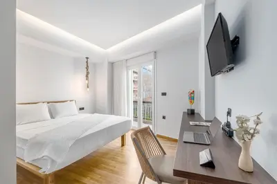 a white bedroom with a bed and a desk at Rizes Suites Metro Dafni in Athens