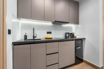 a kitchen with white cabinets and a black counter top at Rizes Suites Metro Dafni in Athens