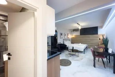 a living room with a kitchen and a room with a piano at Stylish & Elegant Apt in Pagrati in Athens