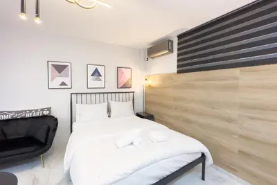 a bedroom with a white bed and a black chair at Stylish & Elegant Apt in Pagrati in Athens